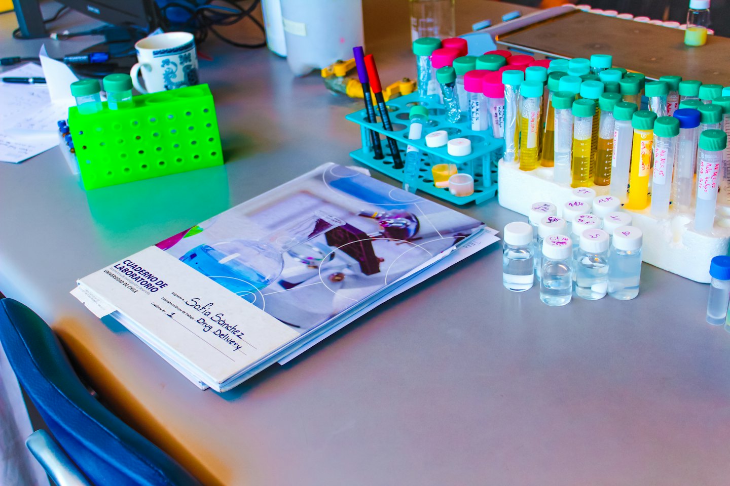Test tubes and vials with liquids on a laboratory workbench.